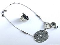 Photo of the pewter necklace with steel chain and removable dangle alongside the pewter ring with black leather knot, showing overall appearance and materials