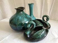Four-piece lot of Blue Mountain Pottery: two swan planters, round vase, and slender vase in green and teal glaze.