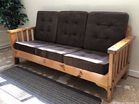 Left angled view of solid wood couch with chocolate brown cushions showing rustic frame and cushion condition.