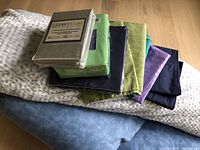Photo showing all bedding items including sheets, pillowcases, and pillows stacked together on floor.