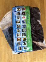 Natural Instinct throw blanket folded with visible label showing multiple horse images and brand details, on wooden floor.