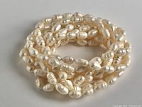 Photo of coiled white freshwater pearl necklace with oval, rice-shaped pearls.