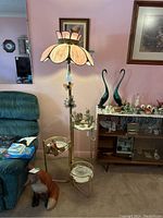 Full view of the brass floor lamp with glass shelves and stained glass flower petal lamp shade in living room setting.