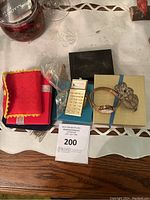 Overview of assorted jewelry on table including cloth pouch, calculator pendant watch, rose gold watch and floral brooch