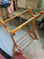 Photo showing a wooden blanket stand with two horizontal bars for hanging and a base support bar.