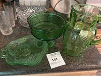 Photo showing the set of green Depression glass including a pitcher, pedestal bowl, and a handled tray with round dish.