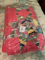 Folded multicolor patchwork quilt sealed in plastic bag on bed