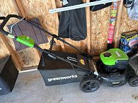 Side view showing mower body, handle, grass bag, and wheels