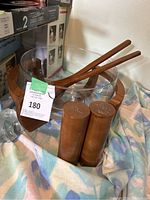 Salad bowl and shakers with utensils arranged on fabric.