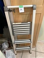 Photo of folded foldable step ladder, aluminum frame, two wide steps, gray and silver color.