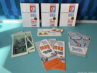 Shows the three New York World's Fair special history and token books, two souvenir pamphlets, two ticket stubs for a 30-minute ride, and three vintage travel maps of the Long Island Rail Road along with several fare tokens scattered around.
