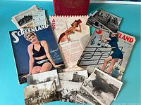 Photo of lot with vintage paper items on blue surface, includes postcards, Screenland magazines, sketch pad, and red calendar.