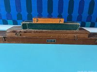 Photo of three wooden/boxed cases, one large wood case with K&E Leroy label and two smaller boxes stacked on top.