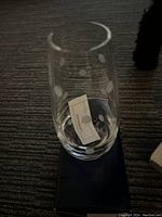 One clear crystal bud vase with an etched polka dot design, placed on a dark surface, showing a tag inside the vase.