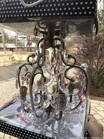 Photo of unopened bedroom chandelier inside its packaging showing intricate metal framework and pink and clear crystal-like beads.