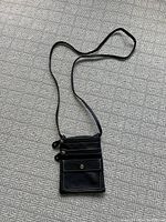 Full view of the black leather shoulder purse showing two zipper closures and one snap button closure with long strap