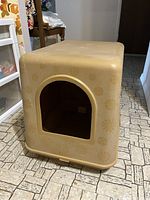 Side angled view of hooded enclosed cat litter box showing textured floral pattern and arched entrance.