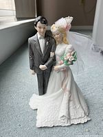 Close-up photo of the bride and groom porcelain figurine showing detailed wedding attire and facial features