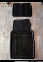 Two black rubber floor mats, one larger with a contoured edge and one rectangular, displayed on tiled floor to show texture and size difference.