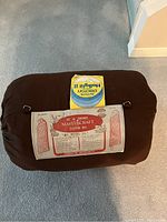Photo showing Mastercraft sleeping bag rolled up in a dark brown nylon cover with cotton interior, including product label with specifications.