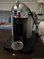 Front view of the Breville Vertuo Nespresso coffee machine showing metal and plastic build, drip tray, and water dispensing area.