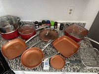 Full view of all cookware pieces including stock pot, saucepans, frying pans, skillets, steamer insert, fry basket, and glass lids laid out on countertop