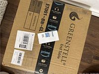 Closed cardboard box labeled Greenstell End Table with Amazon Prime tape and shipping labels.