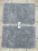 Photo of two rectangular pale blue chenille bath mats side by side on tiled floor.