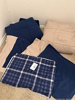 Photo of 2 comforters and 5 shams in navy and beige colors arranged on carpet floor