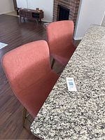 Two salmon pink/mauve bar stools next to kitchen counter showing fabric upholstery and style
