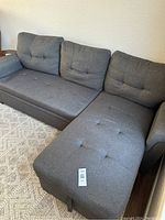 View of the bluish gray sectional sofa with chaise and tufted cushions, showing the overall condition and color.