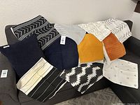 Photo showing full assortment of 11 pillow covers in various colors and patterns and a glimpse of pillow inserts.