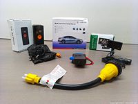 Multi-function jump starter box, car air pump box, cables including clamps and yellow power cable extension on a flat surface