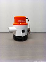 Front angle view of the Seaflo 3700 GPH bilge pump showing orange top, white body, black base with intake holes, and white hose outlet.