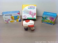 Four bubble toys: a white/red bubble machine with solution bottle and three boxed and loose bubble guns in colorful packaging.
