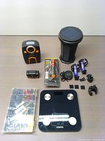 Photo showing solar bug zapper, Renpho digital scale, flashlight in packaging, stopwatch timer and various accessories laid out on a table.