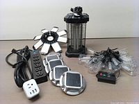 Full view of all items arranged on table showing the LED garage light, mosquito killer lamp, solar lights, power tap, and string lights.