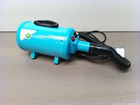 Side view of blue pet grooming machine with power cord and hose attachment.