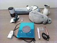 Full view of all self care items: lantern, heated pad, nail duster fan, flat iron, wrinkle steamer, nail drill with heads and power adapter.