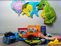 Photo showing inflatable sea animal balloons, boxed construction vehicle toy, blue remote control car with clear oversized wheels, and balloon pump box.