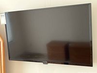Front view of black flat screen TV mounted on wall.