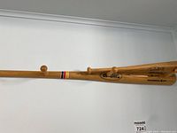 Wall-mounted Cooper wooden baseball bat with four pegs used as a hat rack.
