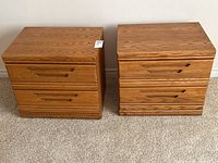 Front view of two matching wood veneer bedside tables, side by side on carpeted floor.