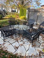 Wide view of entire patio set including table and four chairs arranged on stone patio