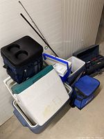 Photo showing the stacked coolers (both hard and soft sided) along with fishing rod and tackle box.