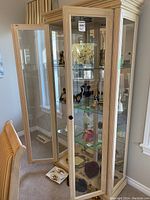 View of the curio cabinet with the door open showing the three interior glass shelves and some displayed items inside.