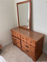 Front and side view of wooden dresser with attached mirror, showing drawer wear and hardware.