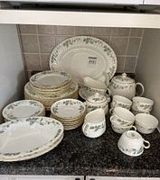 Overview of stacked dinner and salad plates, oval serving platters and tea service on countertop
