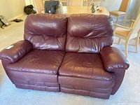 Front view of brown leather loveseat showing two seats, armrests, and padded backs.