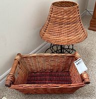 Wicker basket with rectangular shape and wooden handles, showing internal and external weave detail.